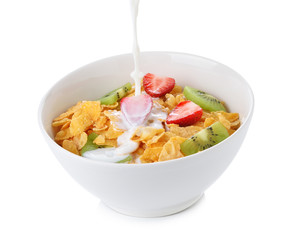 pouring milk into bowl of corn flakes with fruit on white backgr