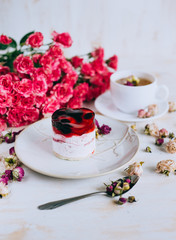 Still life with herbal tea, cake and roses on wooden background