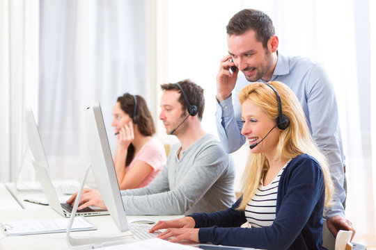Manager training a young attractive people on computer