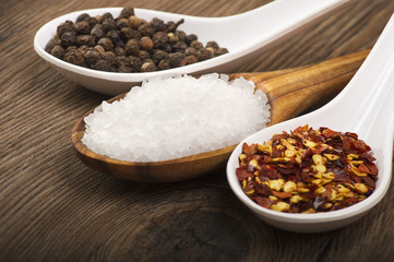 spoons with pepper, salt, chili pepper on wooden table
