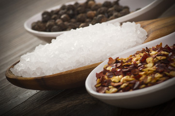 spoons with pepper, salt, chili pepper on wooden table