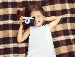 Funny child shooting vintage old retro camera and having fun on