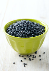 black lentils on table in bowl