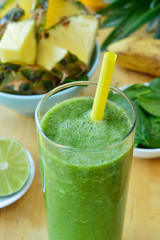 Green spinach and pineapple smoothie on table.