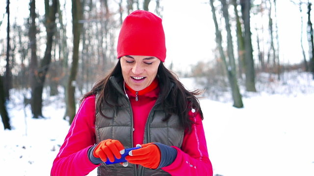 Jogger checking cellphone in the snowy park, steady, slow motion