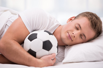Young man lying under a blanket with soft ball