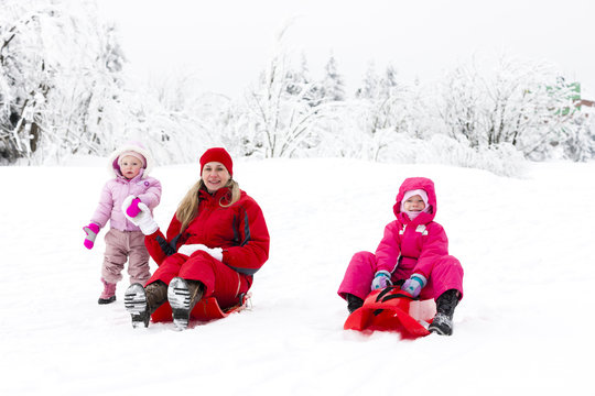 mother and her little daughters with bobs in snow