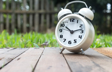Classic alarm clock on wood against nature background