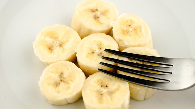 Slow motion mashing of cut pieces of banana into paste with fork