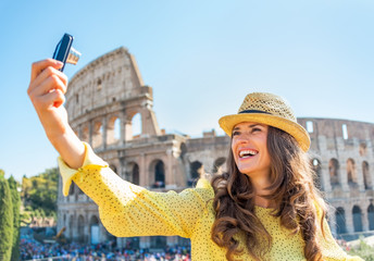 Obraz premium Happy young woman making selfie in front of colosseum in rome