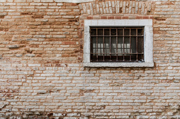 Ancient brick wall texture. Window with grill and railings.