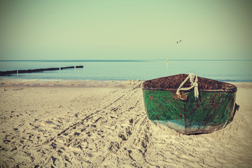 Plakaty  Retro filtrowany obraz starej zardzewiałej stalowej łodzi na plaży.