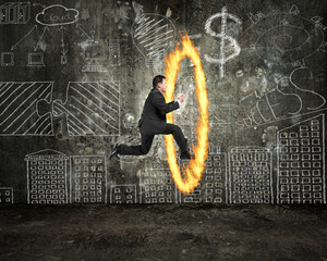 Businessman holding tablet jumping through fire hoop with doodle