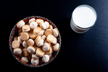 Small cookies in the Turkish bowl and glass of milk on a black t
