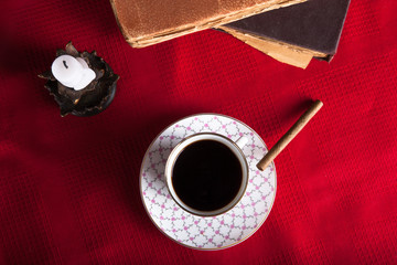 Old books, cup of coffee, cigarette and ancient candle on the re