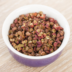 Szechuan Pepper - Szechuan peppercorns in a purple bowl.