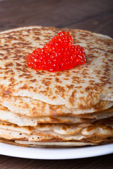 Red caviar on the stack of Russian pancakes - blini on a wite pl