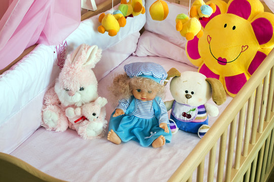 Various soft toys in the cot with orange linen