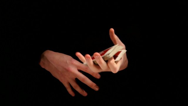 Magician shows his trick with playing cards on black background