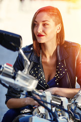 Fototapeta na wymiar Biker girl in a leather jacket on a motorcycle