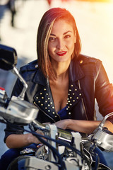 Obraz na płótnie Canvas Biker girl in a leather jacket on a motorcycle