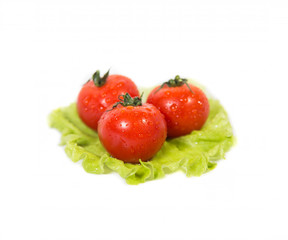 Three tomatoes lying on a sheet of green salad