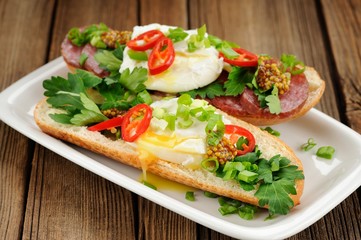 Fototapeta na wymiar Poached egg sandwiches with chili, scallion and salami