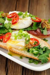 Fototapeta na wymiar Poached egg sandwiches with chili, scallion and salami