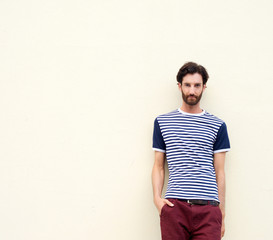 Cool male fashion model with beard leaning against wall