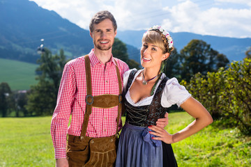 Paar in Tracht steht auf Alm in den Alpen