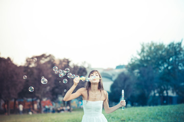 beautiful young woman with white dress blowing bubble