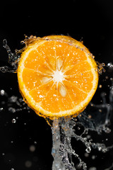 Fototapeta na wymiar orange in water on a black background