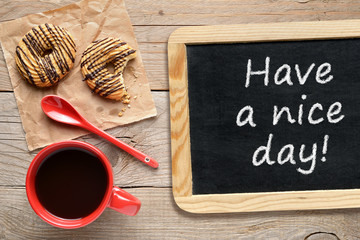 Coffee cup, cookies and chalkboard with phrase Have a nice day!