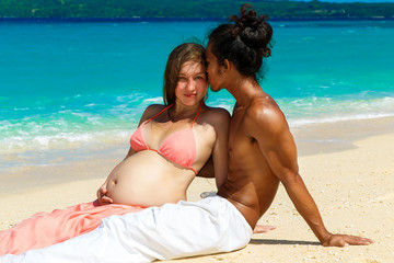 Fototapeta premium Happy and young pregnant couple having fun on a tropical beach.