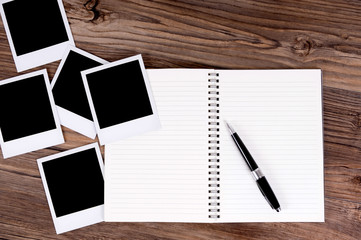 Spiral notebook or photo album with several blank polaroid style frame prints laying on a wood desk...