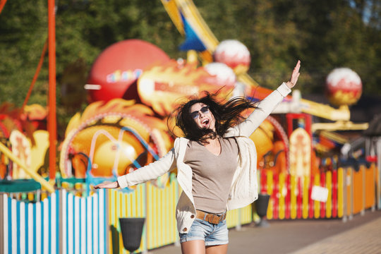 Amusement park rides. A young woman is happy and jumps.
