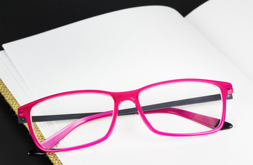 Folded pink glasses on book