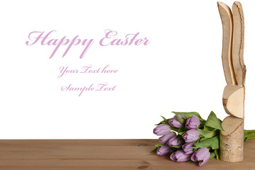 Gruß zu Ostern mit einem hölzernen Osterhasen und lila Tulpen