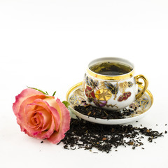Porcelain tea cup with rose flower and dry tea leaves
