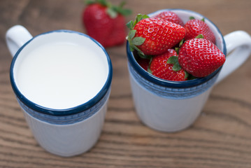Cups filled with  fresh stawberries and milk