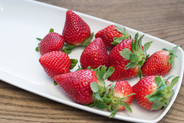 Fresh strawberries  on white rectangular plate staying on dark w
