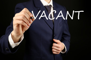 Businessman writing VACANT at transparent whiteboard, close-up