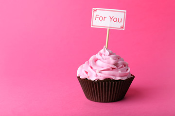 Delicious cupcake with inscription on pink background