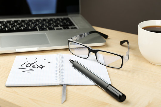 Cup of coffee with note Idea in notebook and glasses