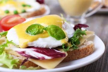 Toast with egg Benedict and tomato on plate on wooden table
