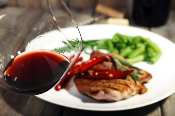 Glass of wine and steak with vegetables