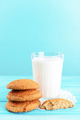 Tasty cookies and glass of milk on color wooden background