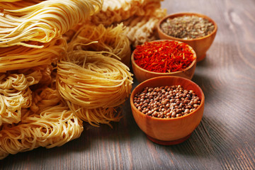 Different dry instant noodles with spices on wooden background