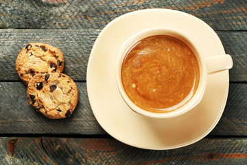 Cup of coffee and tasty cookies on wooden background