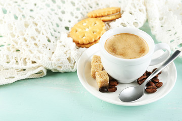 Cup of coffee and tasty cookie on color wooden background
